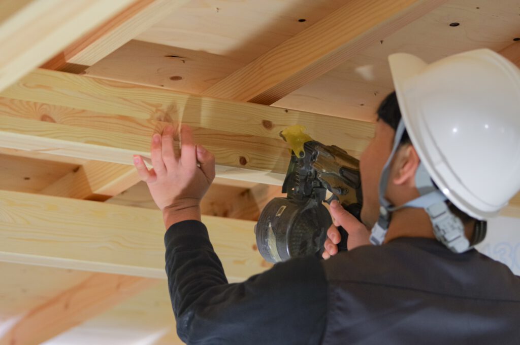 釘打機を木材に打ち付ける作業員