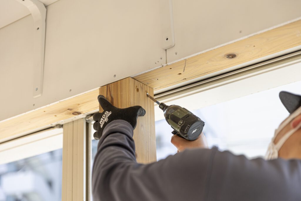 柱を電動ドライバーで固定する作業員